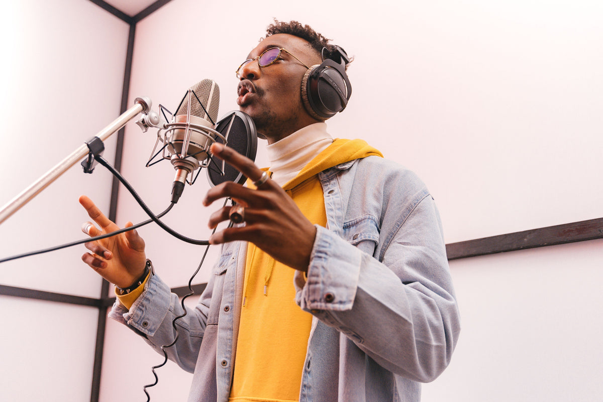Independent rapper at studio microphone checking phone while recording