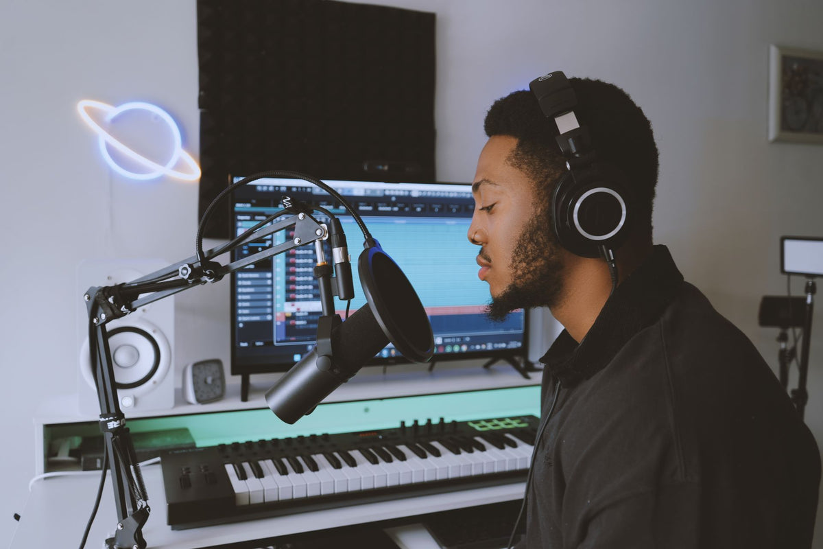 Home studio setup with FL Studio on screen and neon Saturn sign
