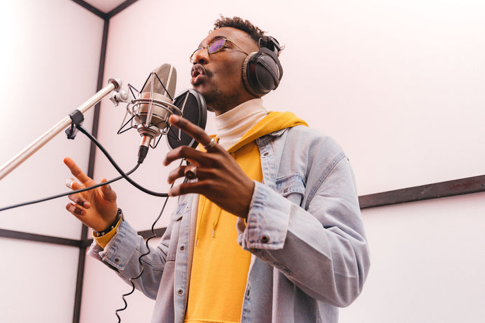 Independent rapper at studio microphone checking phone while recording