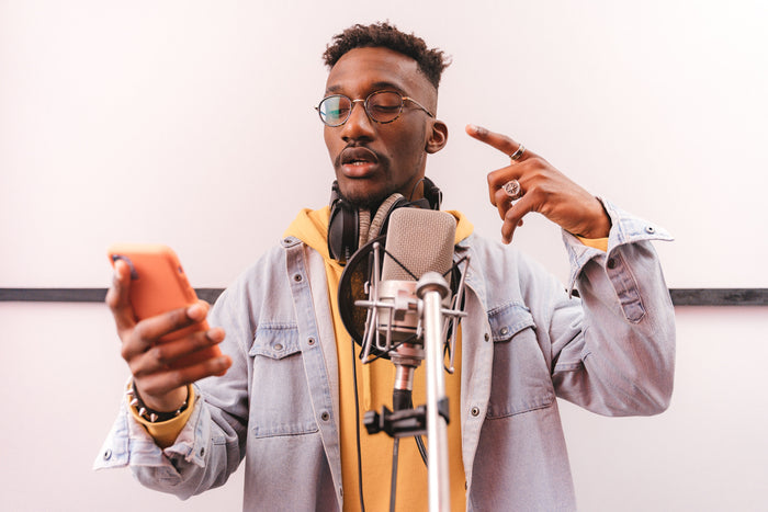 Rapper at studio mic reviewing phone while making production decisions